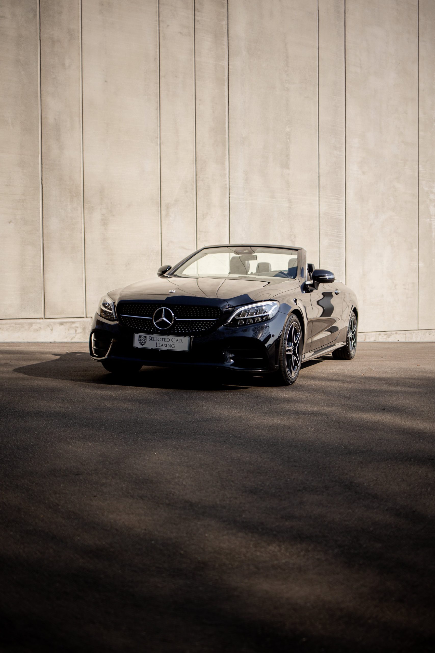 Sort Mercedes-Benz C-Klasse Cabriolet foran betonbygning