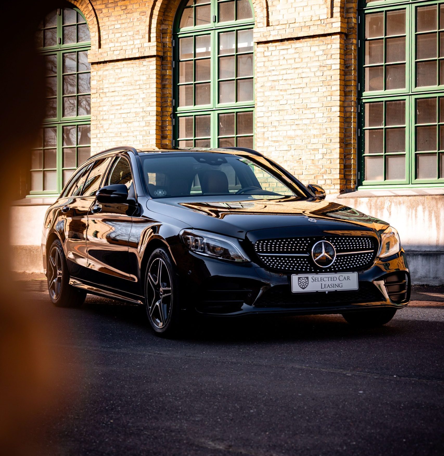 Sort Mercedes-Benz C-Klasse stationcar foran murstensbygning